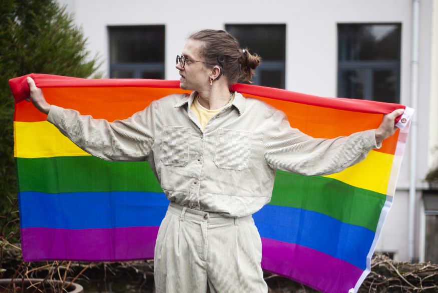 Persoon met een cochleair implantaat houdt de regenboogvlag vast