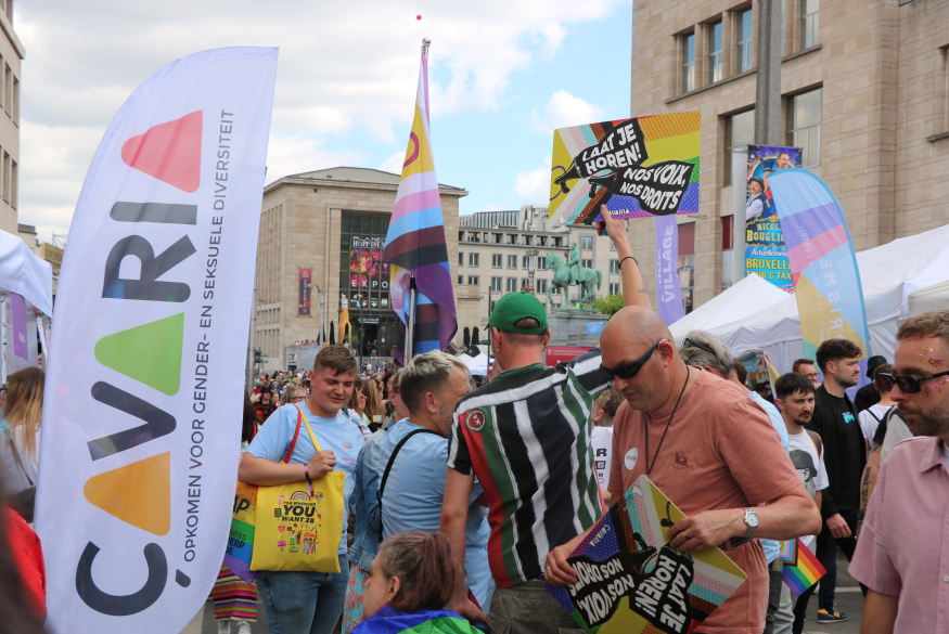 Groep personen op Pride, met bannervlag van çavaria en bord met 'laat je horen'
