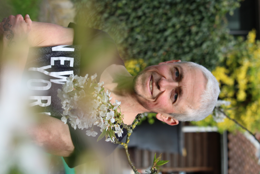 Simon met op de achtergrond een struik en een tuinhuis