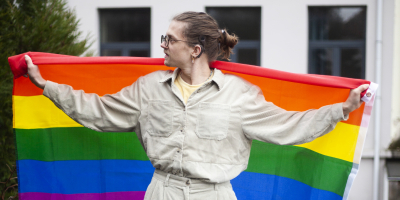 Persoon met een cochleair implantaat houdt de regenboogvlag vast