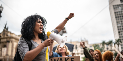 Persoon die megafoon vasthoudt en vuist in de lucht steekt 