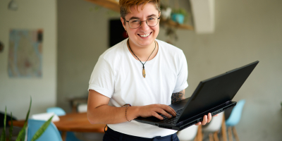 Solliciteren Persoon met witte t-shirt staat recht en heeft laptop vast