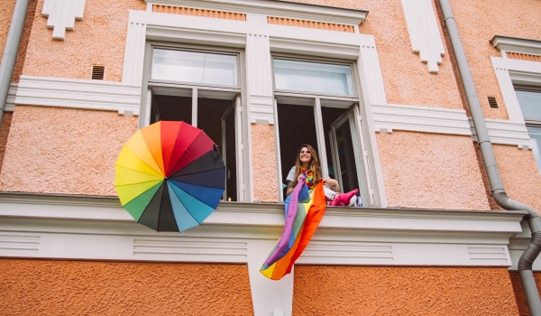 person in window with rainbow flag