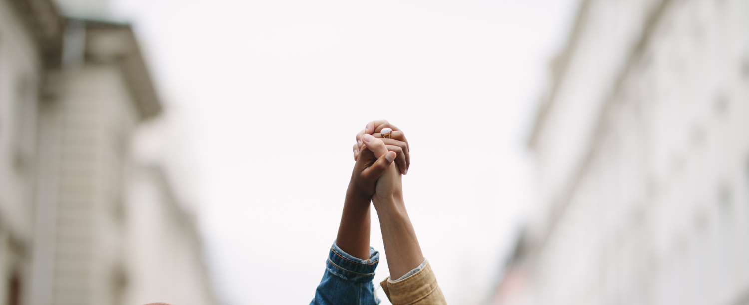 Twee personen die handen hoog in de lucht tussen hen vasthouden