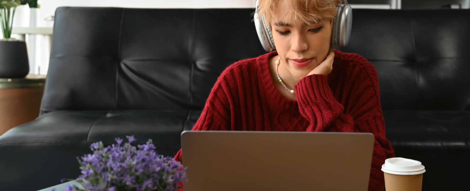 persoon die achter laptopscherm zit met regenboogvlag op achtergrond