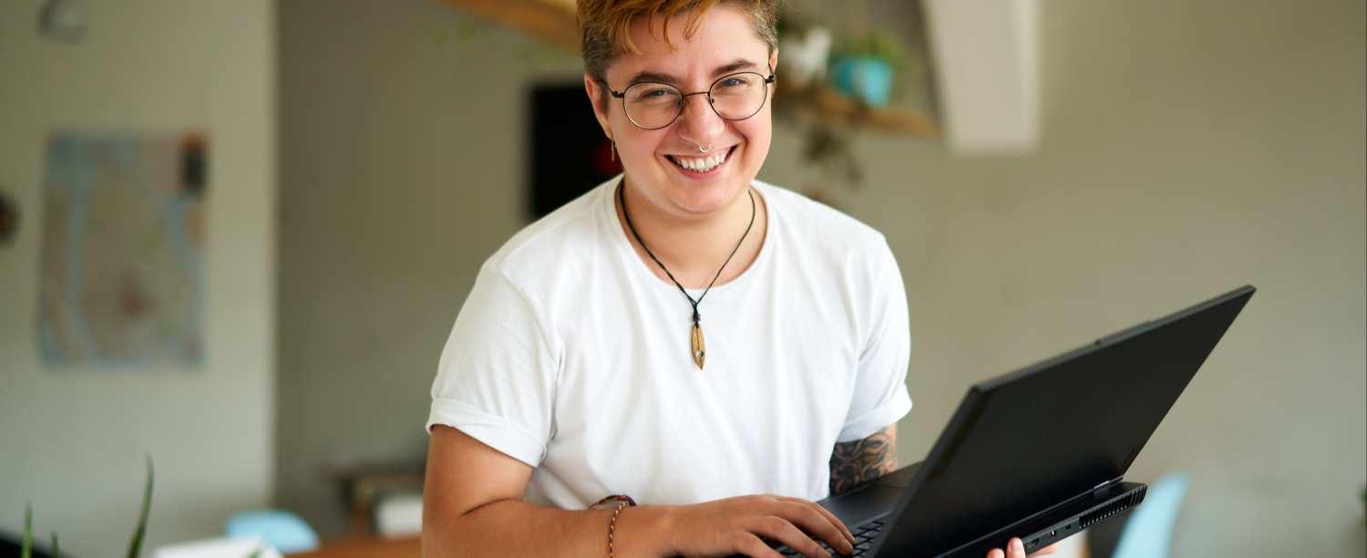 Persoon met witte t-shirt staat recht en heeft laptop vast