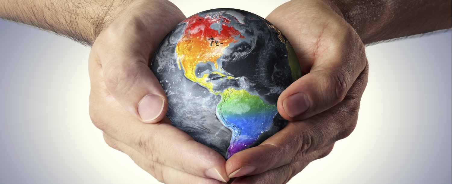 Wereld Twee handen die een wereldbol in regenboogkleuren vasthouden.